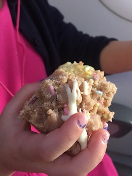A little girl holding a birthday crumb cake in her hand