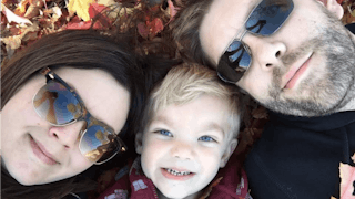 Lisa Marie Cheney lying on fallen leaves with her husband and son