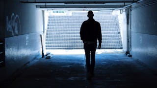 A person walking in a dark underground tunnel with graffiti
