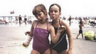 Two small girls having a playdate on the beach, and posing next to the sea