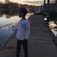 A boy standing and looking at the lake 