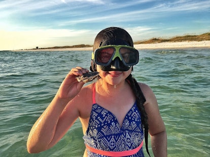 A child snorkeling and finding treasure in the water of Panama City Beach