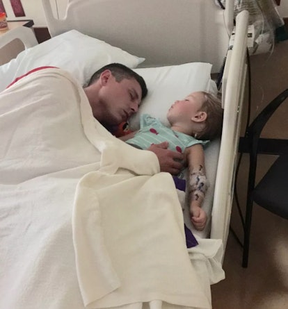 A father lying next to his daughter in a hospital bed