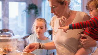 Mother holding her child while cooking in the kitchen