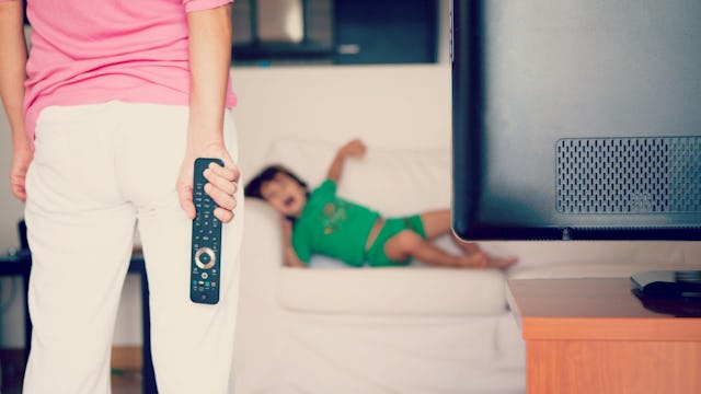 A woman who has taken away the TV remote from her child who is crying about it in the background