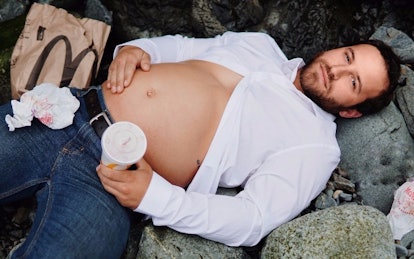 A new dad wearing a white half-buttoned shirt with his belly sticking out lying down with McDonalds ...