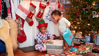 Kids opening Christmas presents in a fully decorated house.
