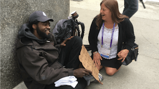 A woman talking to a homeless man on the street
