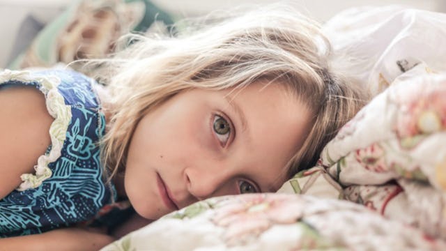 A young sad-looking girl lying on the bed