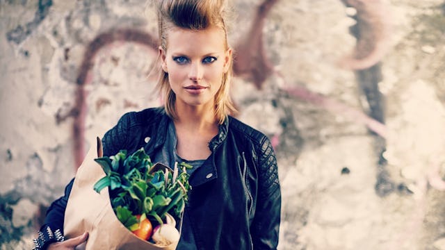 Woman holding a paper bag with vegetables.