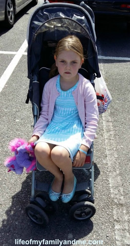  A 5-year-old girl wearing a blue dress and a pink blazer with unicorn toy in a stroller 