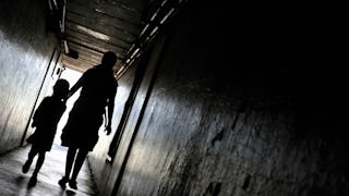 A mother and a child walking in a dark hallway