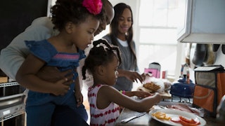 A father and three daughters making breakfast in the kitchen