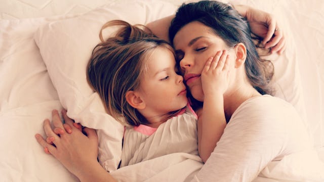 Mom cuddling her daughter in the bed