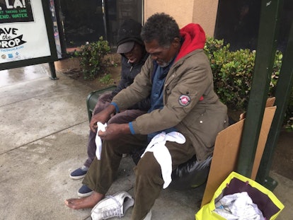 Two homeless people trying out new white socks