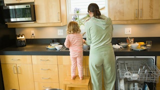 A depressed mother cleaning the kitchen with her small daughter