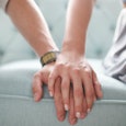 Man and Woman sitting on a sofa, her hand is over the man's hand 
