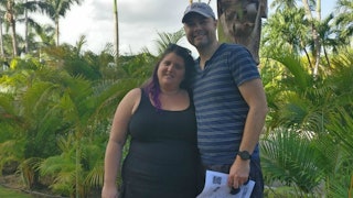 An overweight woman and a man are hugging on vacation