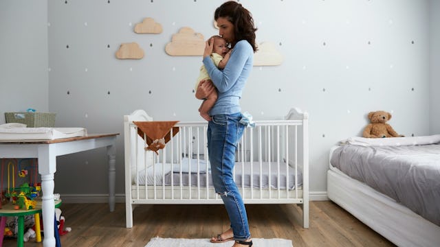 A woman standing in the nursery and holding her baby after being ghosted by her friends