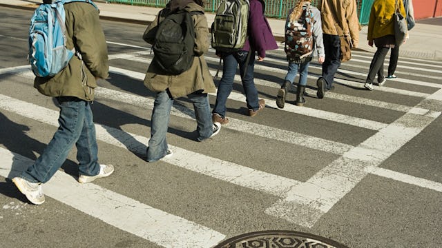 A group of children with backpacks crossing the street