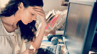 A woman with long brown hair sitting in front of her laptop, who had a miscarriage