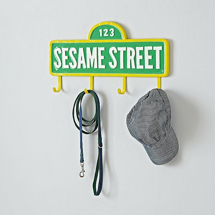 Sesame Street wall sign with white letters and green background while a hat and dog leash are on the...