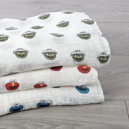 Three swaddle blankets folded on top of one another with Elmo, Oscar the Grouch and Cookie Monster p...