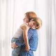 A mom with anxiety and depression in a blue dress holding her little boy in her arms.