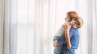 A mom with anxiety and depression in a blue dress holding her little boy in her arms.