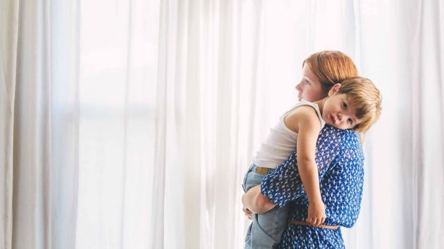 A mom with anxiety and depression in a blue dress holding her little boy in her arms.