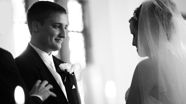 A couple on their wedding day, standing in front of each other, looking into each other's eyes.