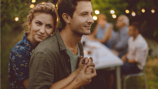 Woman that is in a happy marriage with her husband, holding him from behind while he hugs her