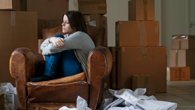 Sad lady sitting surrounded by moving boxes full of stuff during the early days of divorce