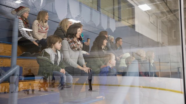 Several parents sitting behind a glass wall while watching their kid's game