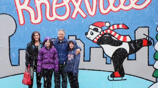 A father, mother, son, and daughter standing in front of a wall with a drawn skating rink and a pand...