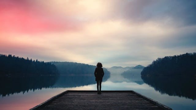A woman standing on a pier with a lake in front of her