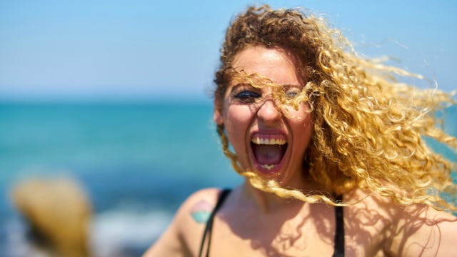 A blonde curly-haired woman on a beach experiencing a manic episode 
