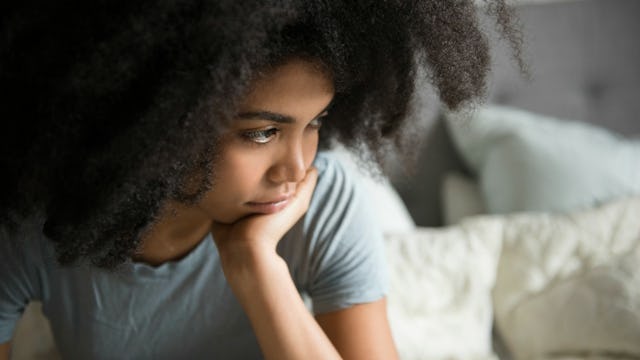 A teenage girl sitting on the bed, terrified of her thoughts 