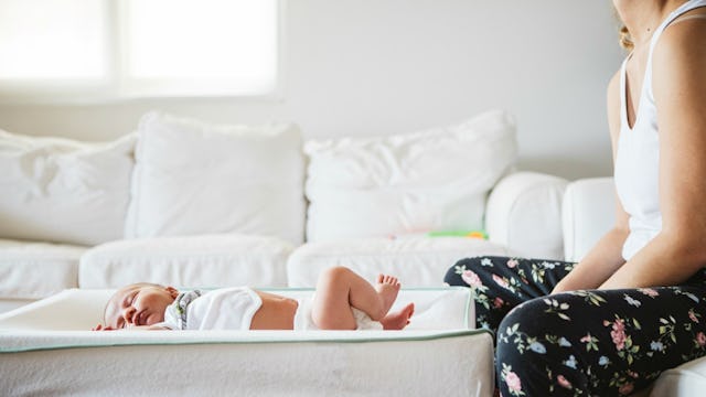 A mother with postpartum depression sitting next to her baby while the baby is sleeping.