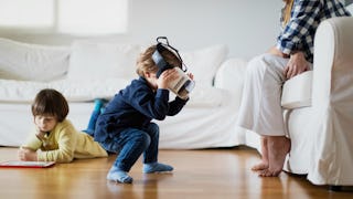 A stay-at-home mother sitting on the couch and watching her two kids playing on the floor