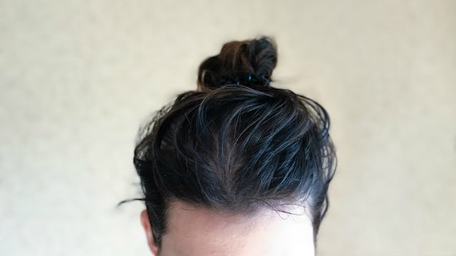 A woman's unwashed hair in a bun