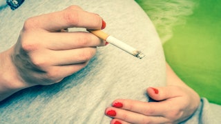 Pregnant woman holding a cigarette. Smoking throughout her pregnancy.