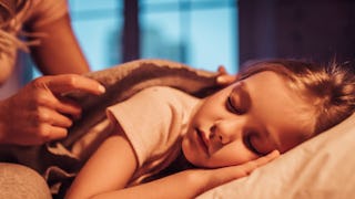 A girl is sleeping while her mom is covering her with a blanket whose mom is strict about bedtime