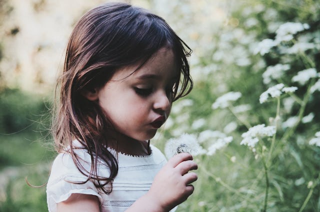A little girl blowing out a dandelion