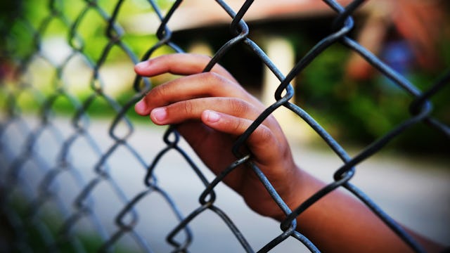 A child's hand leaning onto a wire fence