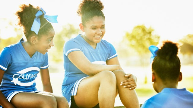 Three cheerleaders sitting and talking