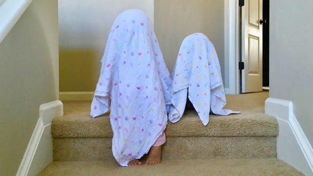 Two kids playing covered with blankets over their head representing kids' imaginary friends