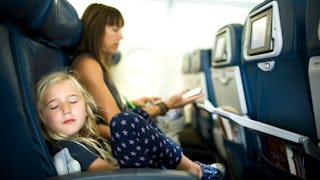 A girl sleeping next to a woman on the plane.