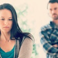 Sad black haired woman with a man behind her looking angrily at her thinking about how they lost the...