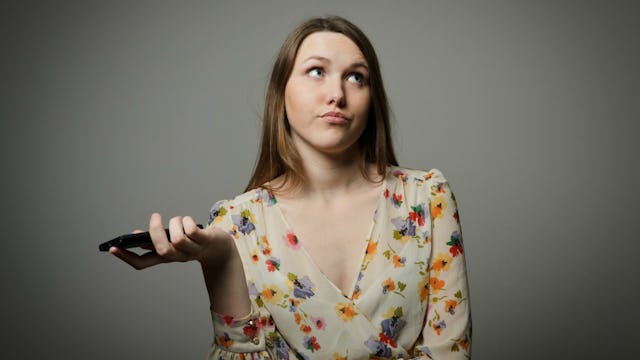 A woman holding her phone with an annoyed facial expression because received an MLM private message